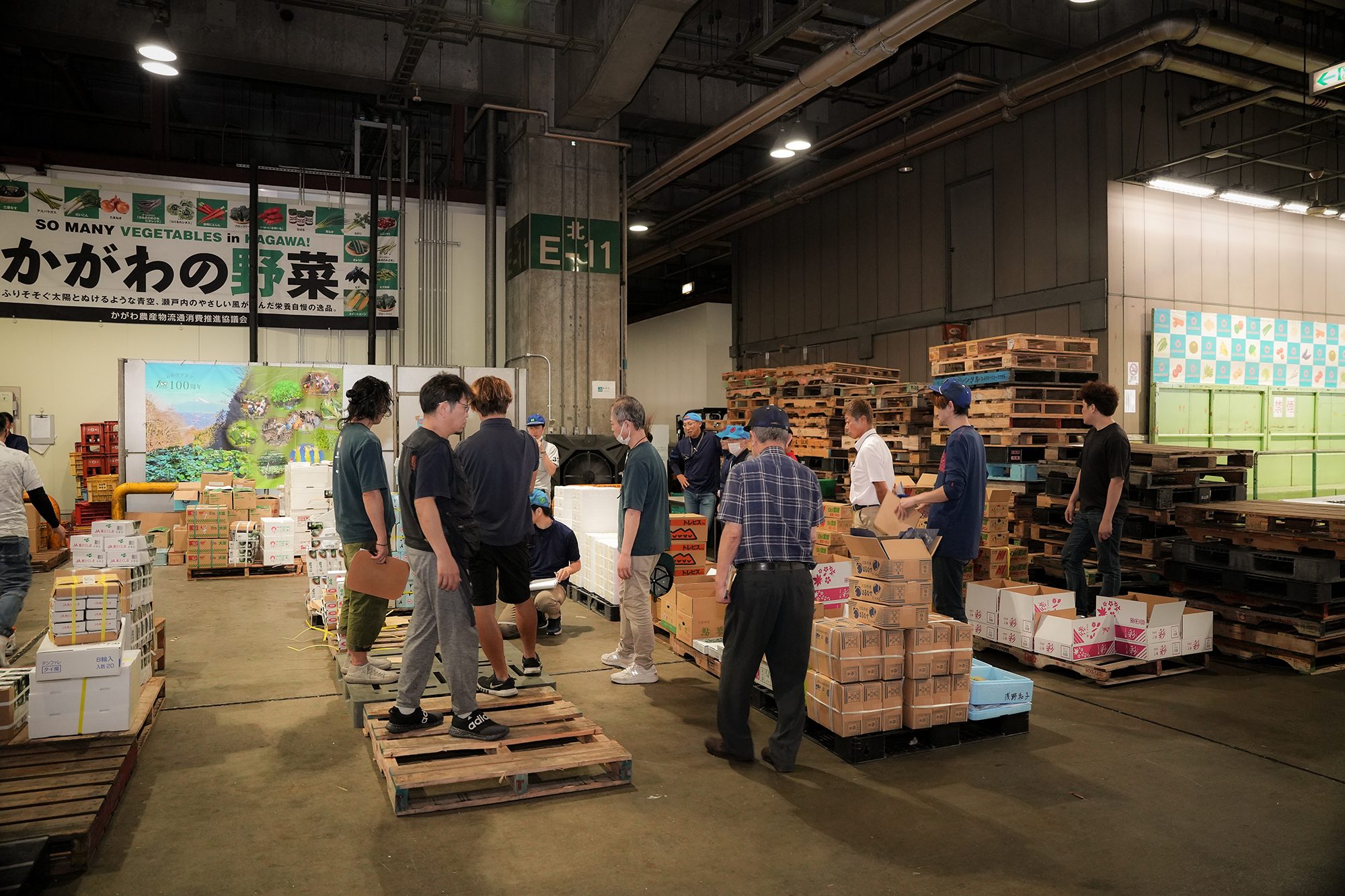 競りの場。並ぶ青果を前に、買受人が品質を見極める現場。