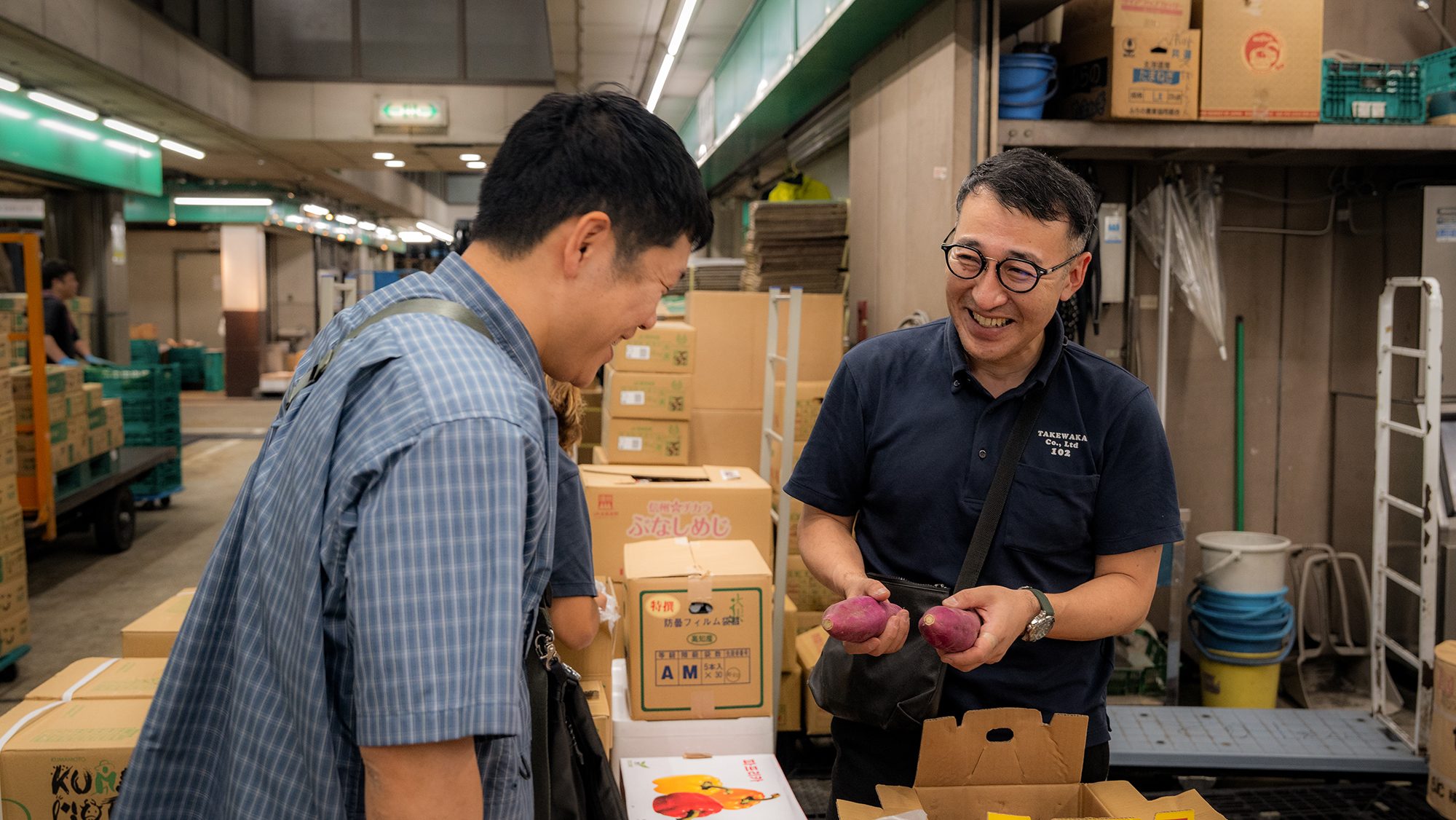 本場の荷受け場で青果の箱を運ぶ社員。朝の現場の空気。