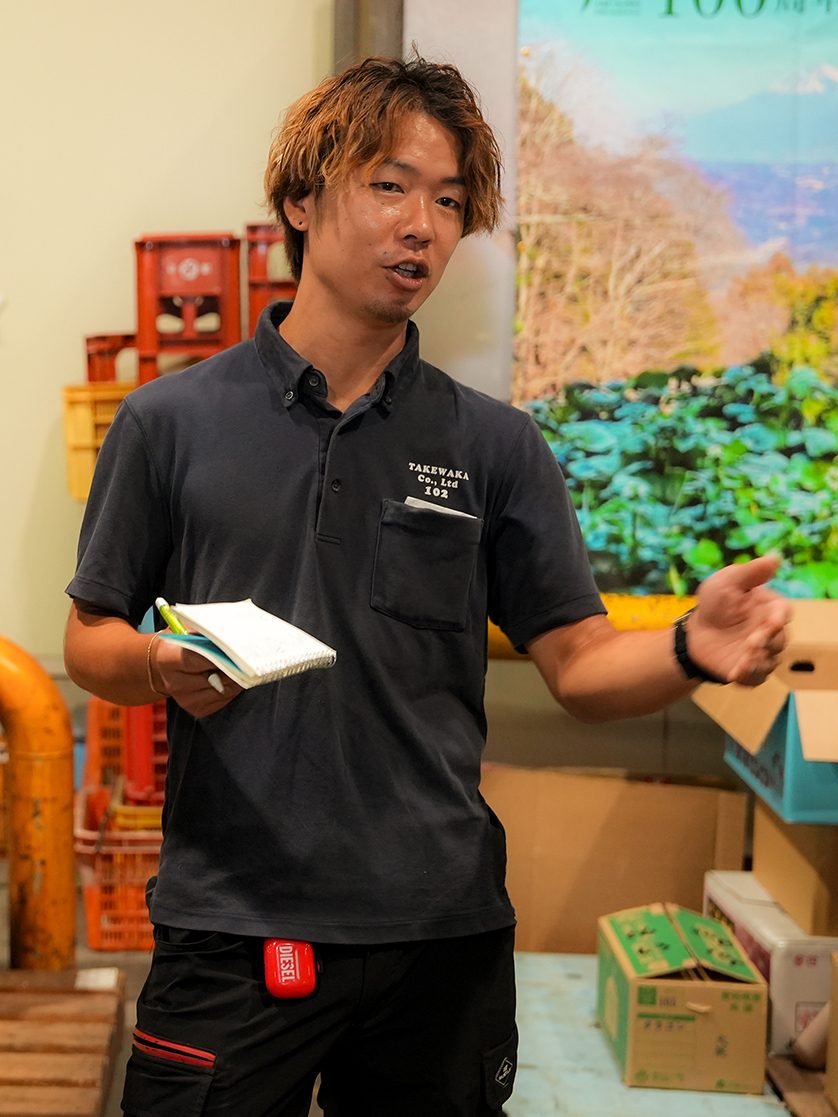 荷受け場で青果の箱に手をかける社員。